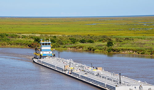 a tug and tank barge unit transporting liquid cargo, likely petroleum or chemicals, on an inland or coastal waterway